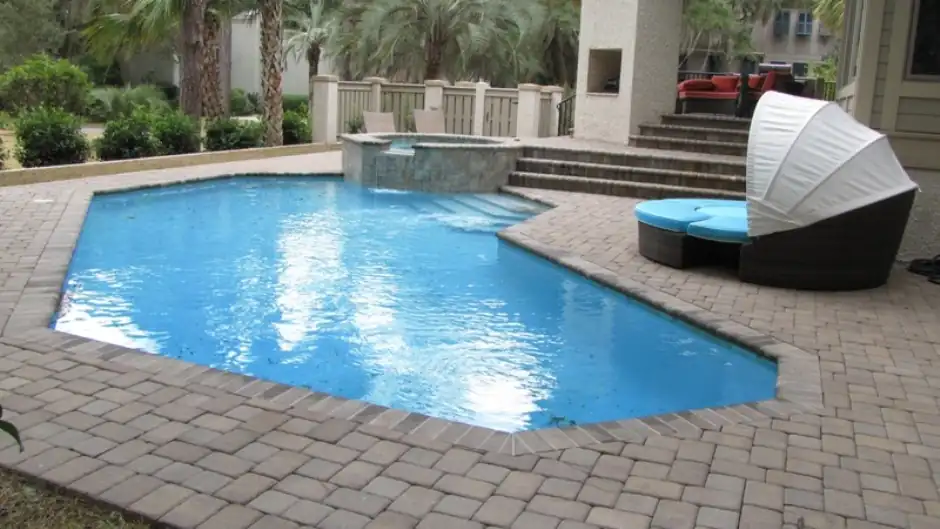Angular pool with a spa and a canopy daybed on a paver deck