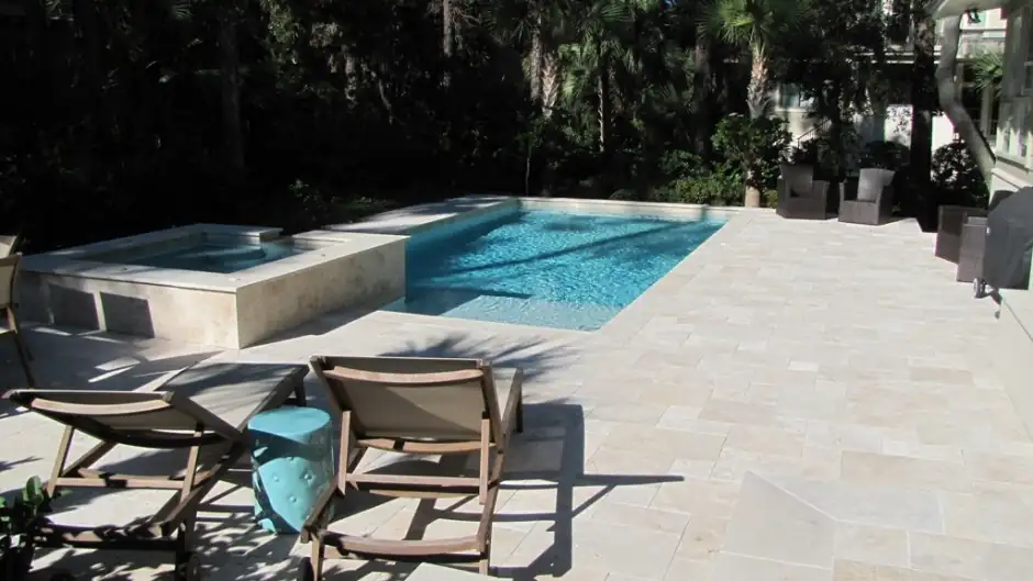 Pool with a raised spa, travertine deck and loungers