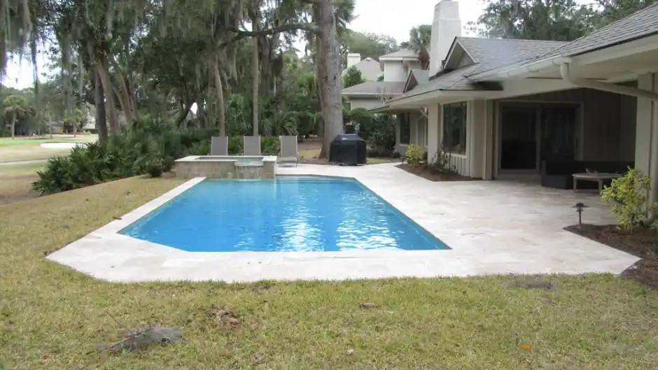 Rectangular pool with a raised stone spa and a golf course beyond