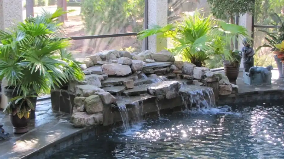 Rock waterfall pouring into an indoor pool with flagstone around it