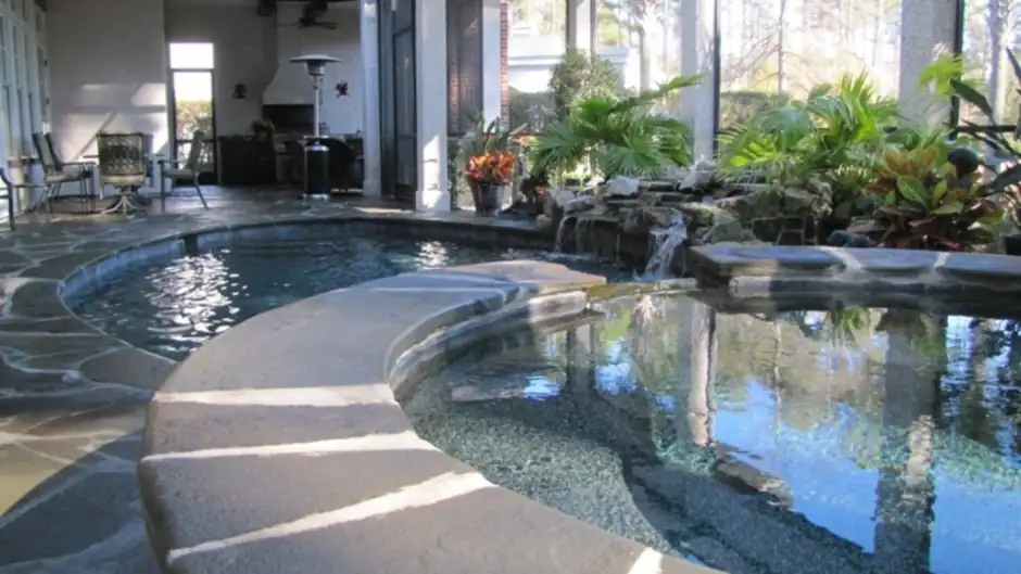 Screened indoor pool and spa with flagstone and a rock feature