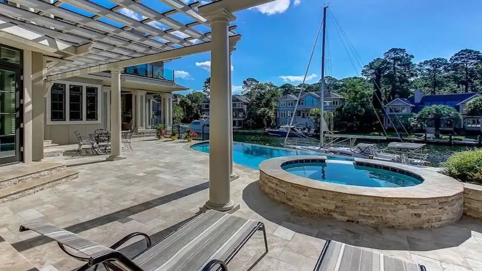 Waterfront estate with a pergola, travertine deck and raised spa beside the pool