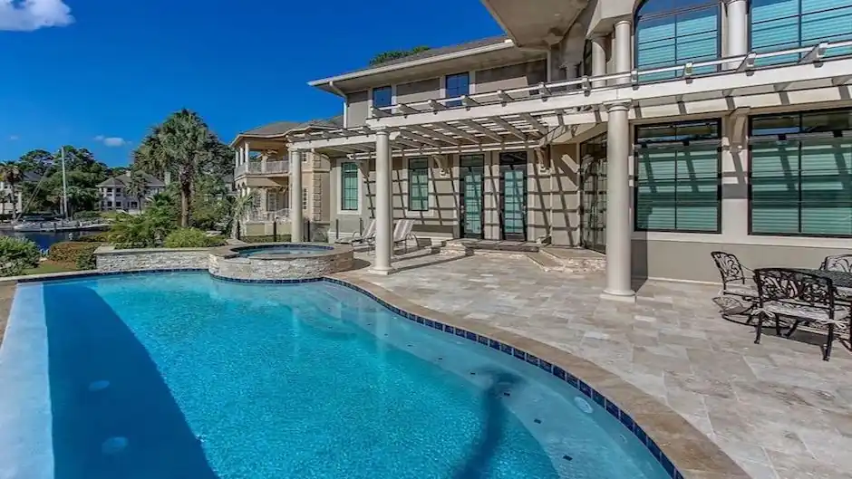Waterfront estate pool with travertine decking and an infinity edge