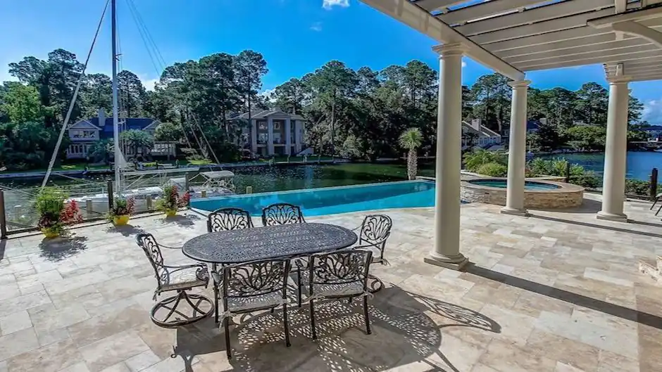 Waterfront pool with a raised spa, travertine deck and a dock on the water